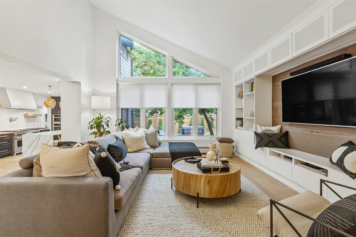 Vaulted great room with shades on tall windows and a built-in media wall