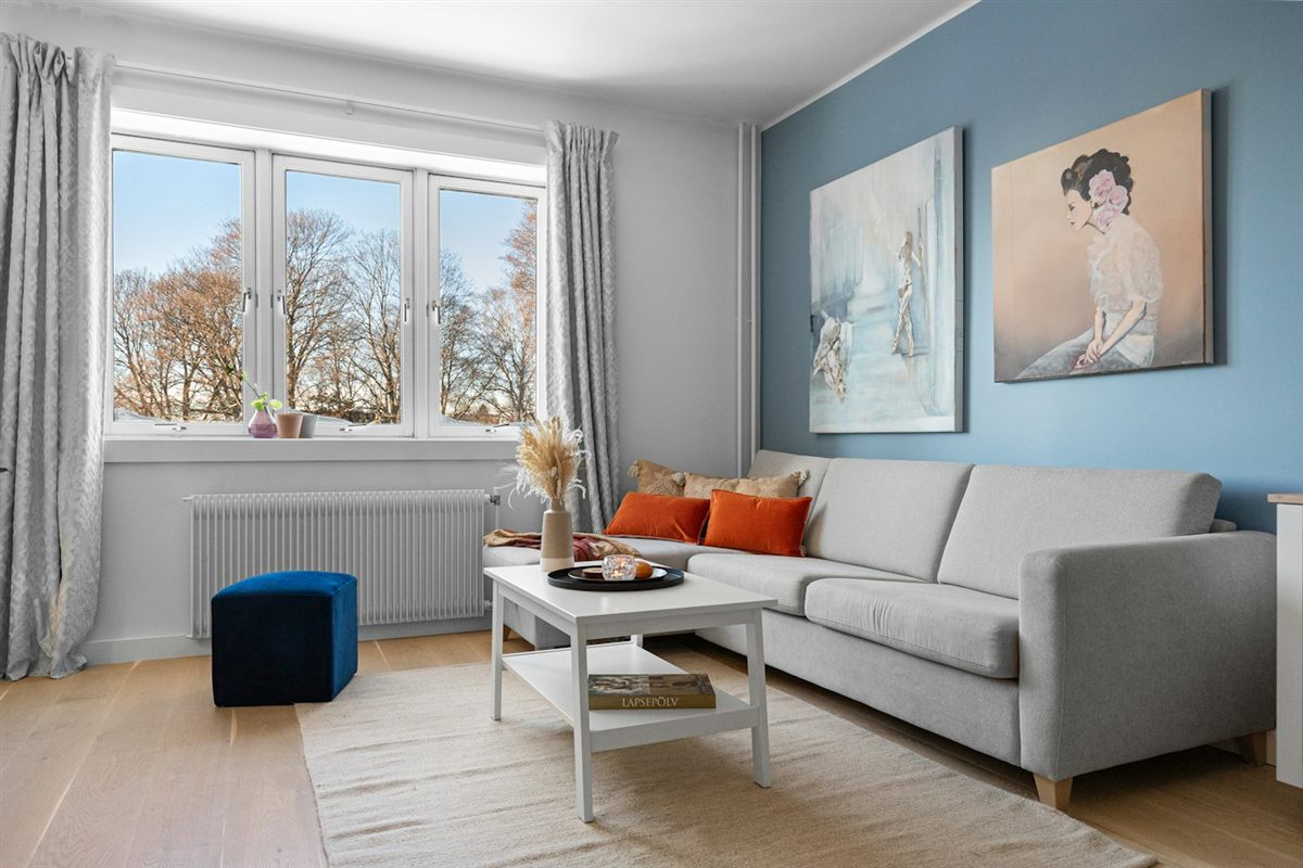 Living room with a light blue accent wall and gray curtains on a wide window