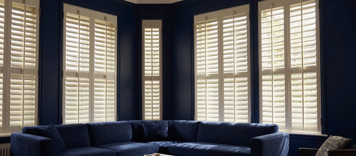 Wood plantation shutters on a bay window in a navy living room